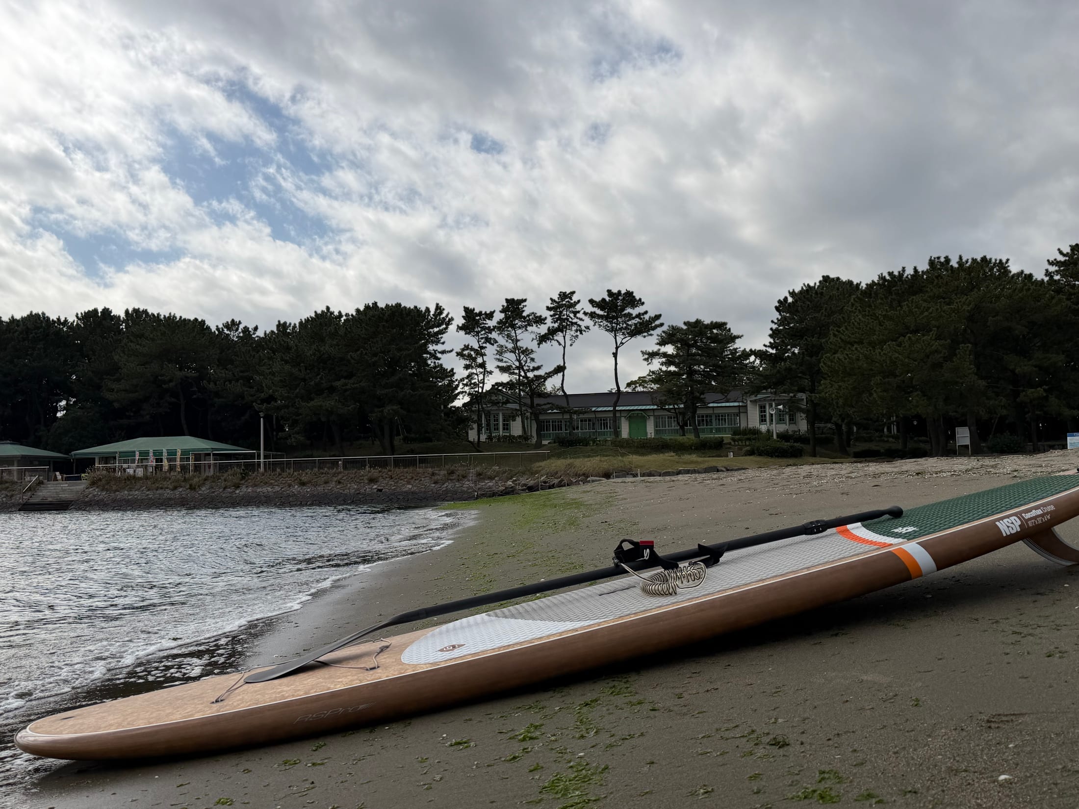 海の公園の砂浜に置かれたSUPボードと静かな波打ち際